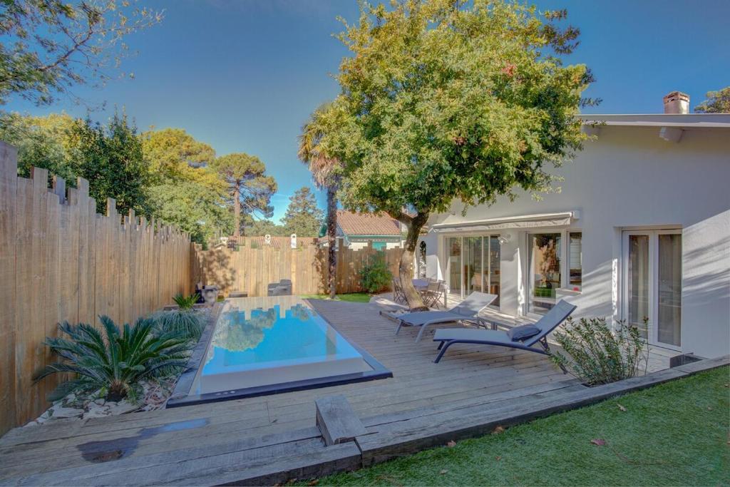 a backyard with a swimming pool and a wooden deck at Maison des Abatilles- Bassin Arcachon in Arcachon