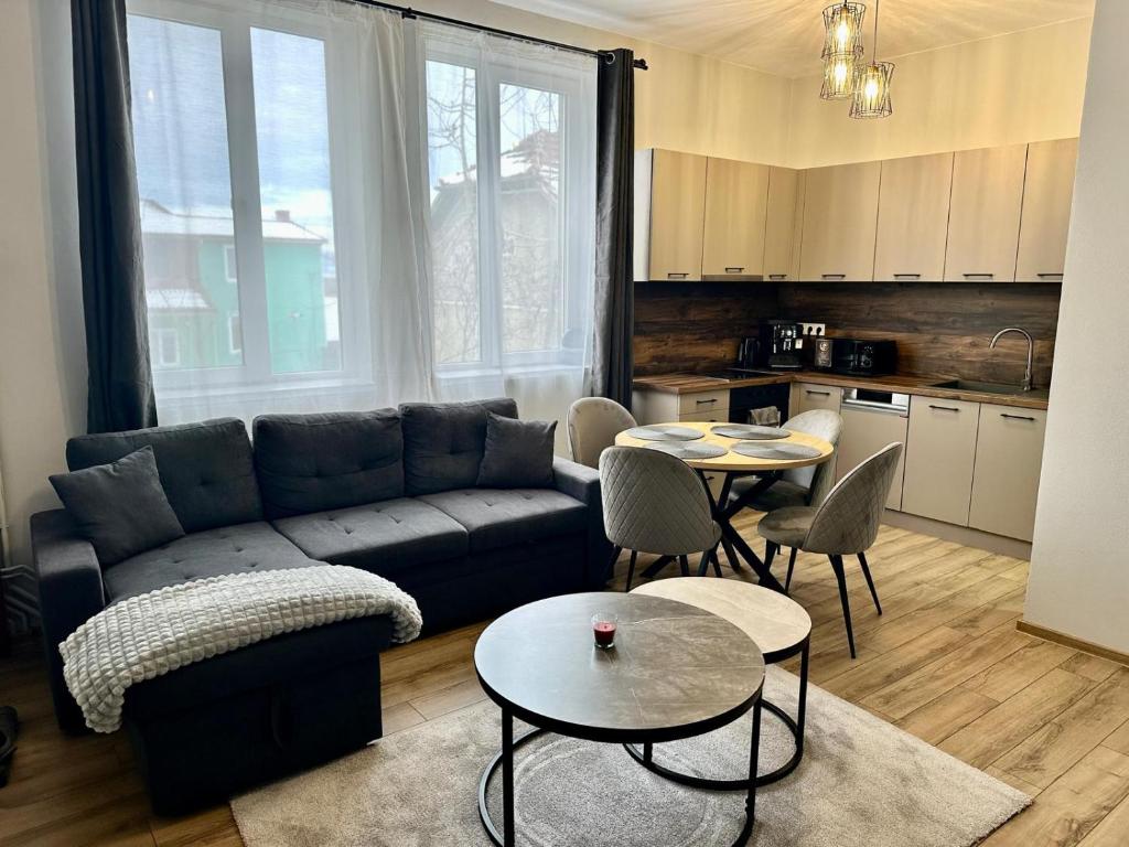 a living room with a couch and tables and a kitchen at DB Guest House 2 in Târgu Secuiesc