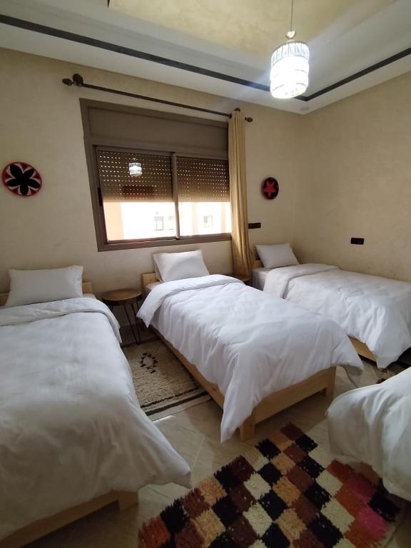 a room with three beds and a window at Nomad Surf Morocco in Imsouane