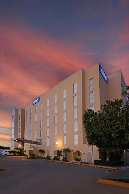 a hotel building with a cloudy sky at dusk at City Express by Marriott Tijuana Insurgentes in Tijuana