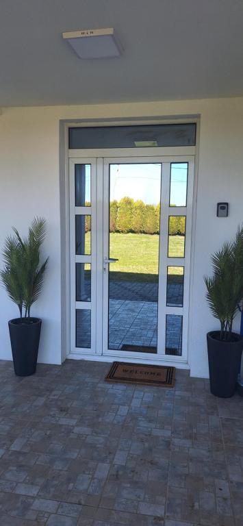 an open glass door with two palm trees in pots at Vila Marjanovic PN in Paraćin