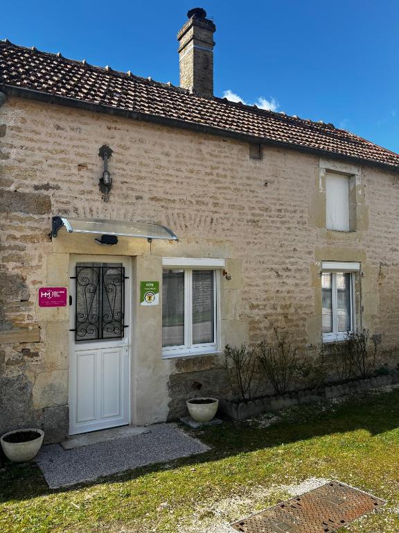 a brick house with a white door and two windows at Gîte au Petit Café in Châteauvillain