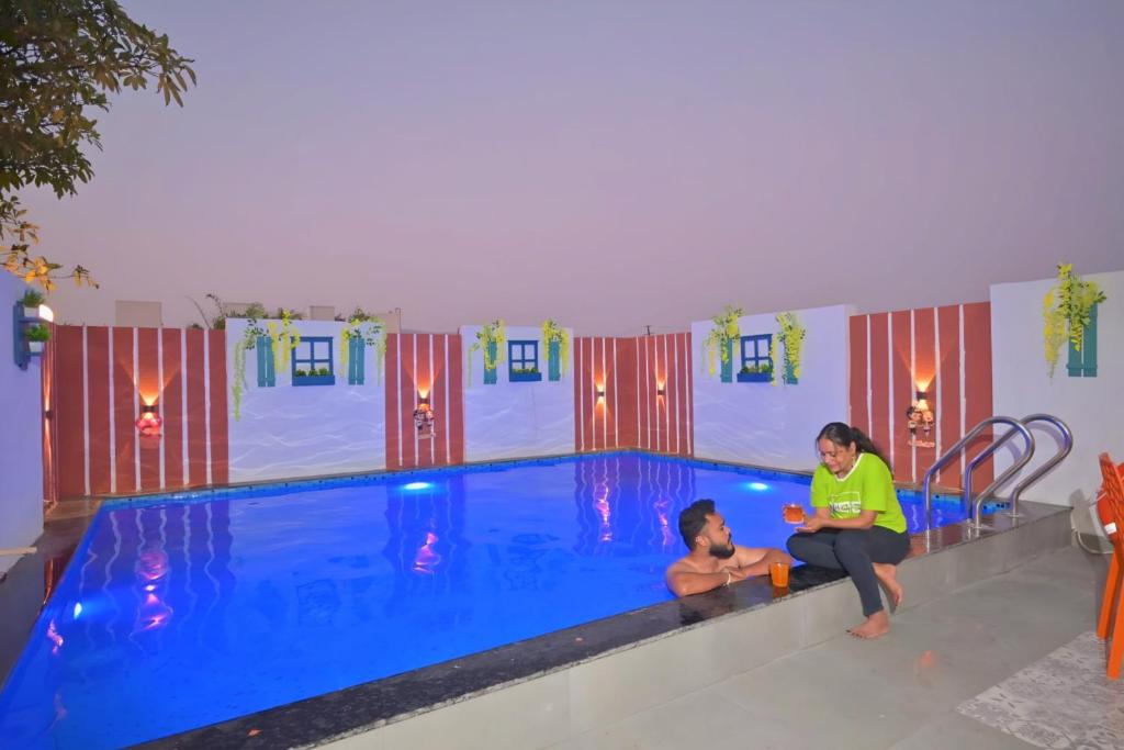 a woman and a man sitting next to a swimming pool at ll EMPYREAN STAY ll THE LOVE SHAKE ll 2BHK ll AC ll PRIVATE POOL ll BACHELORS FRIENDLY ll in Malavli