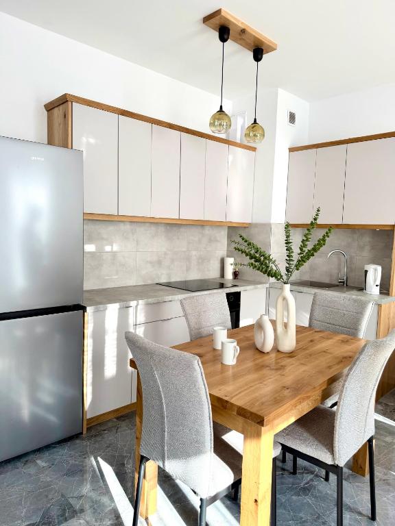 a kitchen with a wooden table with chairs and a refrigerator at Apartament Stare Miasto 2 in Elblag