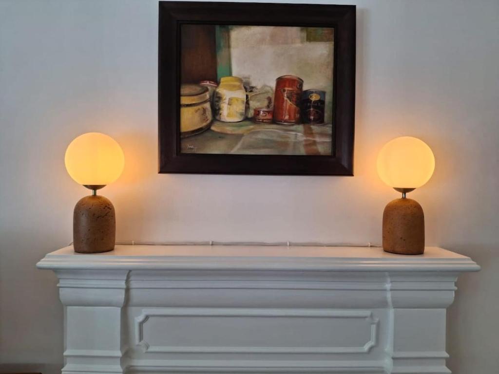 two lamps on top of a fireplace with a painting at Sensitively restored spacious apartment in Durban