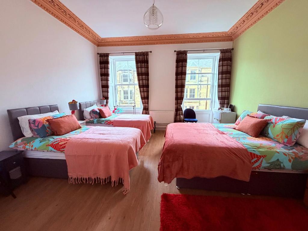 two beds in a room with two windows at Apart Bernard Rooms in Edinburgh