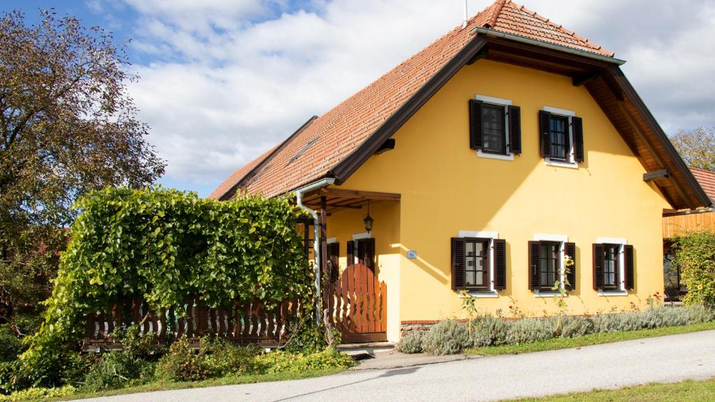 a yellow house with black windows and a fence at Traussegghof Ferienhaus Familie Uhl in Tanzelsdorf