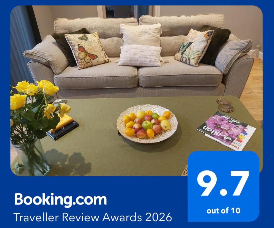 a living room with a couch and a bowl of fruit on a table at Rose Garden Retreat in Rayleigh