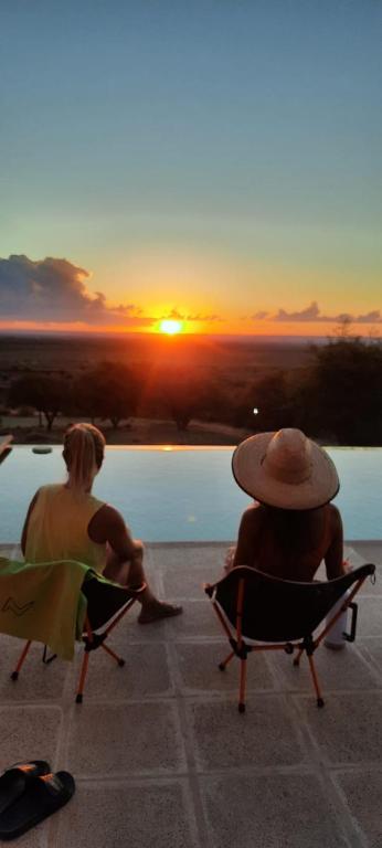 two people sitting in chairs by a pool watching the sunset at GinTonic Rancho in San Luis