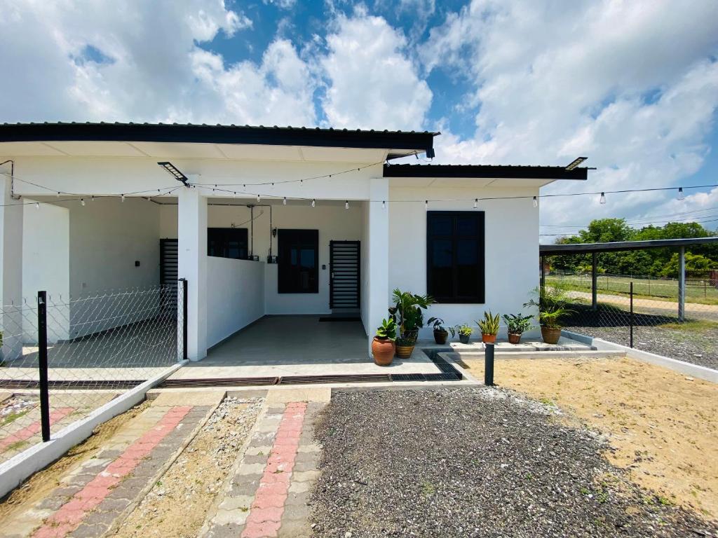 a small white house with a driveway at Homestay Teratak Nailufar in Pekan