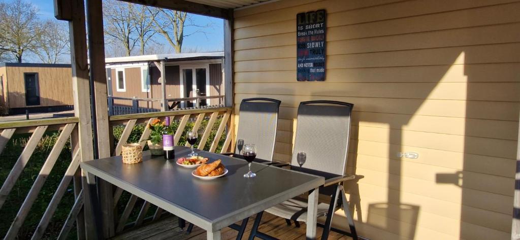 a table on a balcony with a plate of food on it at Chalet B2 900 m vom Strand in Koudekerke