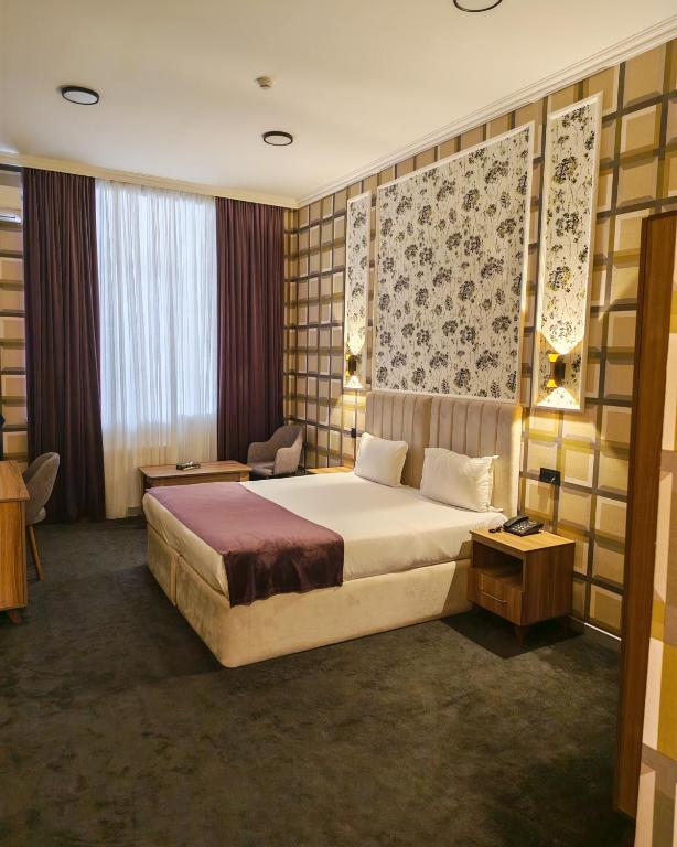 a hotel room with a large bed and a chair at Will Hotel in Baku