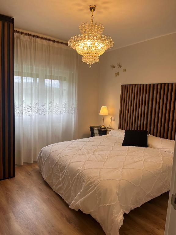 a bedroom with a large white bed and a chandelier at Balcón del cubo in Covaleda