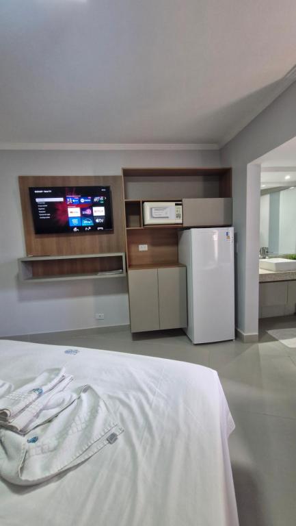 a room with a kitchen with a refrigerator and a tv at Araras Apart Service in Caldas Novas