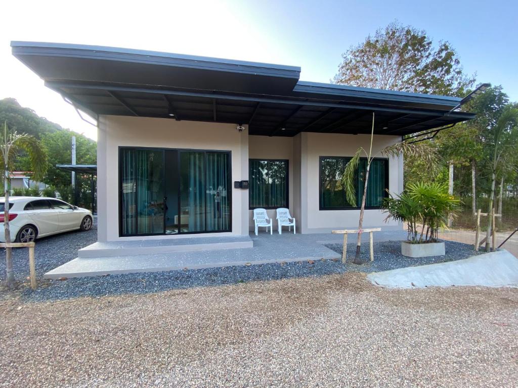 a house with two chairs and a car parked at Cozy Palm Hills in Ban Nong Thale