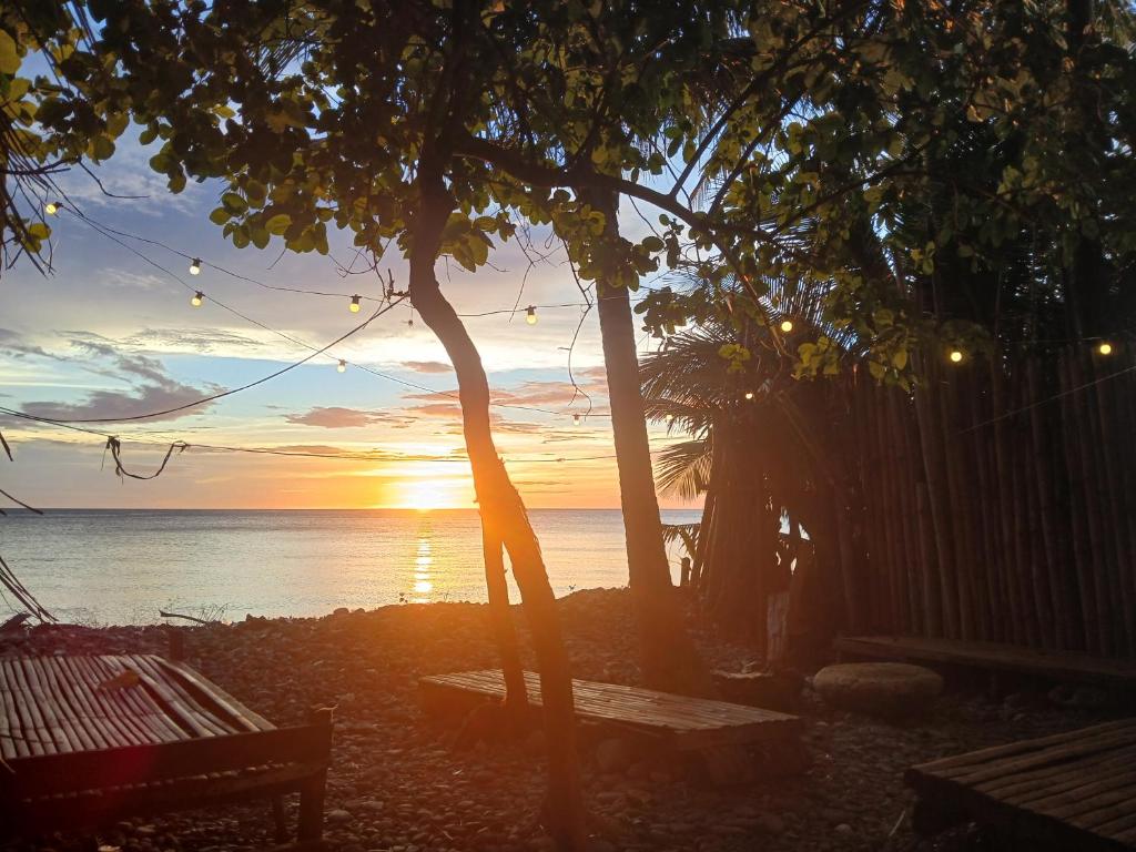 a sunset over the ocean with a bench and a tree at Sunset View Guest House in Camiguin