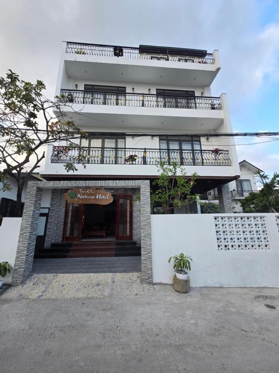 a tall white building with a balcony on top at Tam Coc Natura Hotel in Văn Lâm
