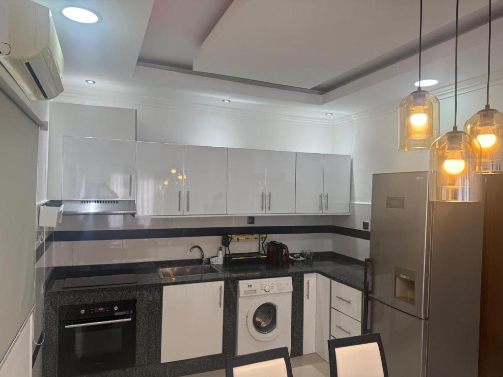 a kitchen with white cabinets and a washer and dryer at House Lima in Lobito