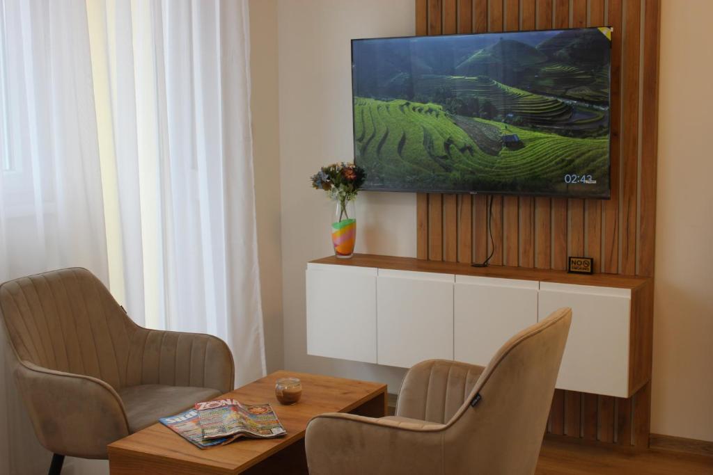 a living room with a table and chairs and a tv at Apartmani Fontana Banja Koviljaca in Banja Koviljača