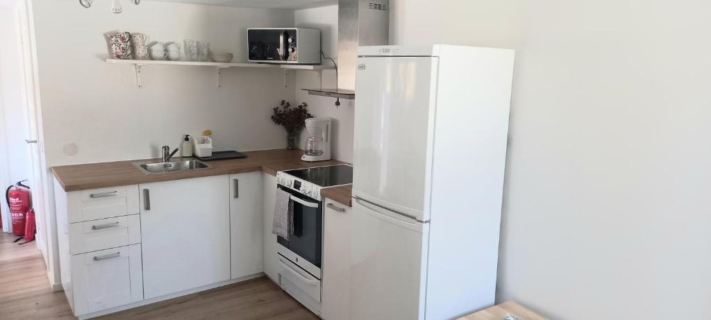 a white kitchen with a refrigerator and a sink at Stuga PETEL in Färjestaden