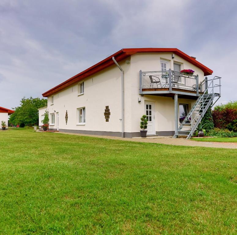 a white house with a balcony and a lawn at Ferienwohnung Meeresbrise in Groß Kordshagen