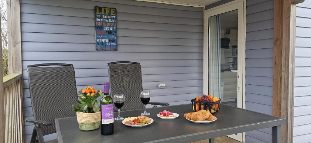 a table with food and wine glasses on a patio at Chalet B1 900m vom Strand in Koudekerke