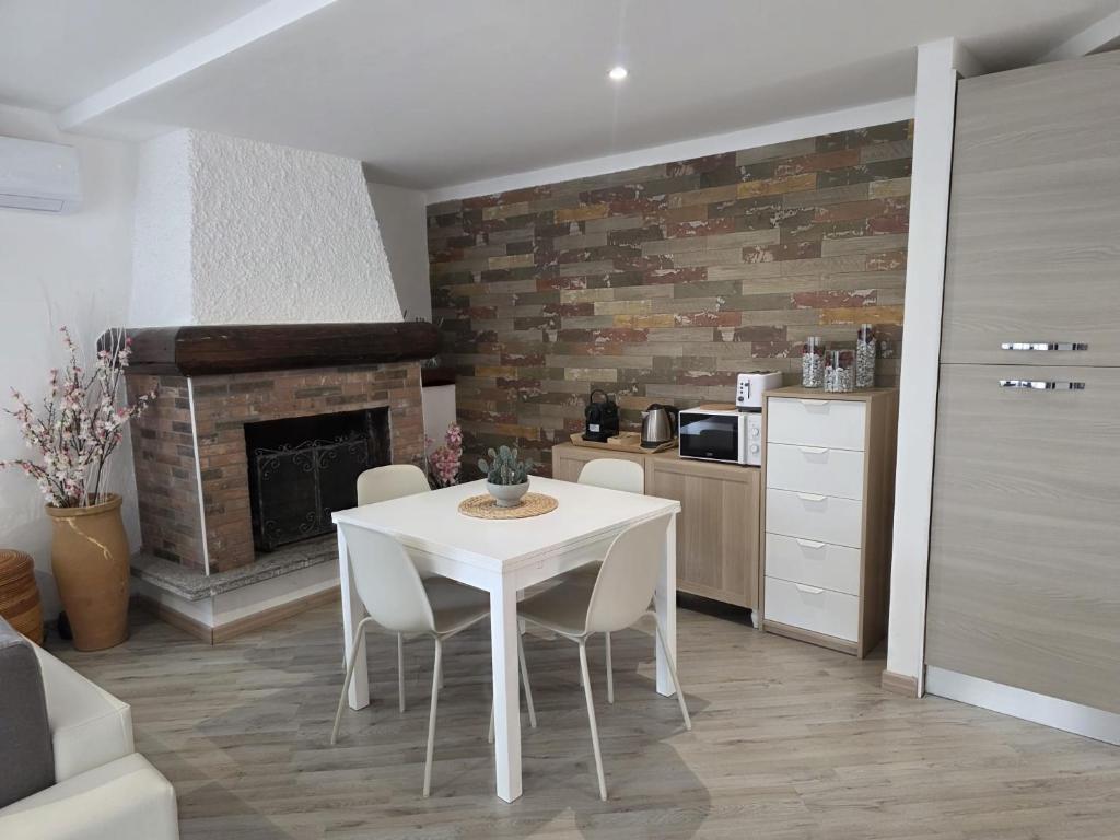 a white table and chairs in a kitchen with a fireplace at Cannella Comfort Apartment in Bellagio
