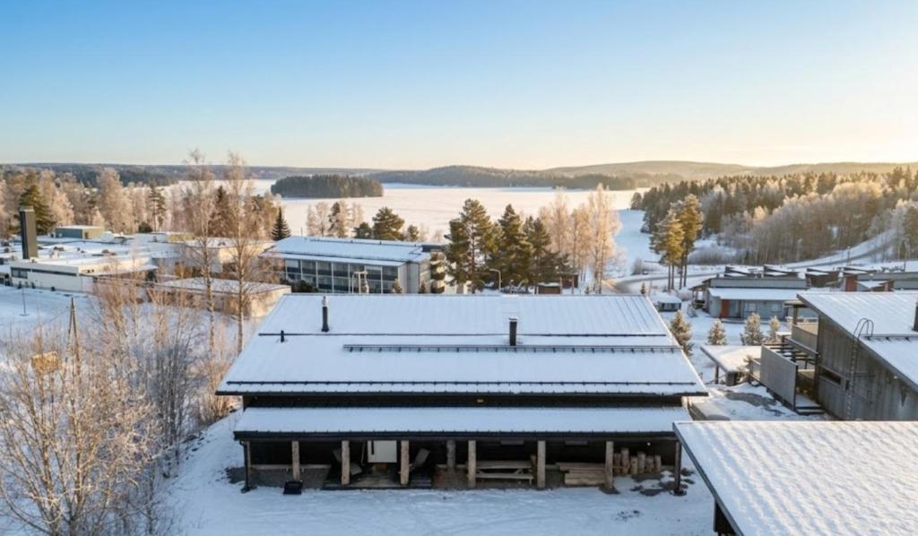 a building covered in snow next to a body of water at Villa West Ellivuori - High Quality 6BR Villa with Jacuzzi in Sastamala