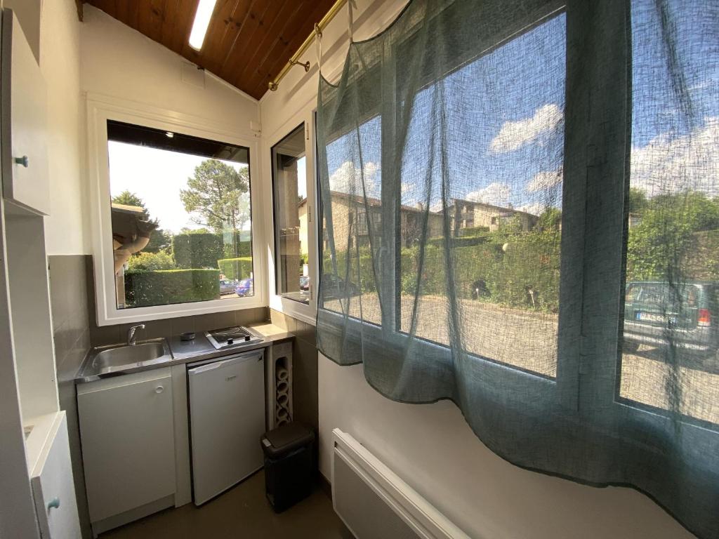a kitchen with a sink and two large windows at Studio Barbotan-les-Thermes in Cazaubon