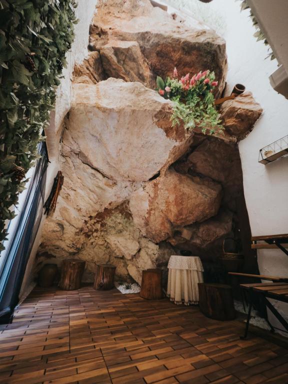 a room with a rock wall and flowers on the wall at Casa de la Cueva in Figueroles