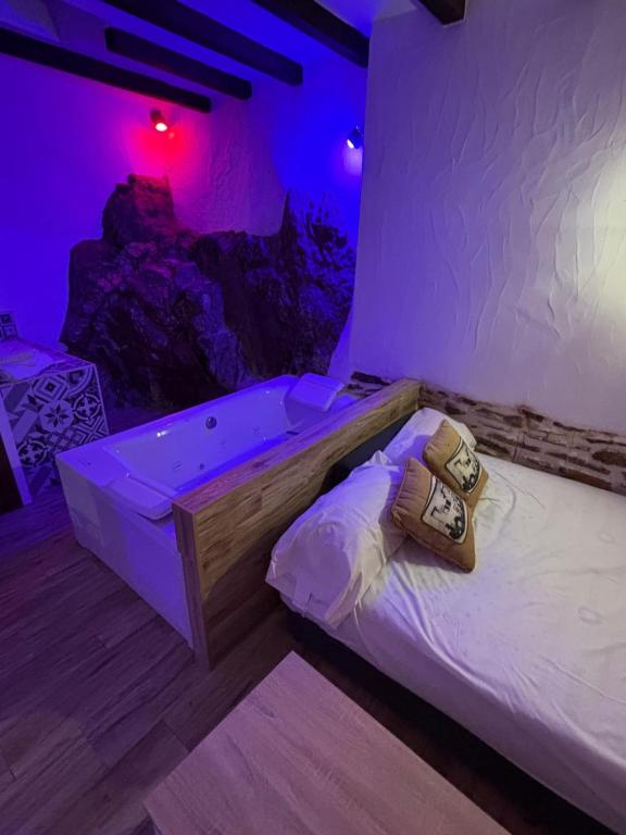 a bed in a room with purple lights at Los Tumbaos - El Tumbao Hidromasaje entre roca natural in Laroya
