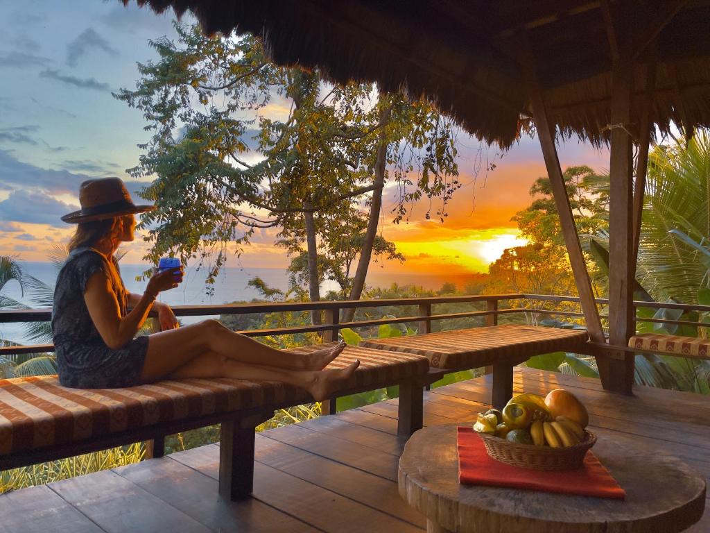 a woman sitting on a bench watching the sunset at Finca Exótica in Carate