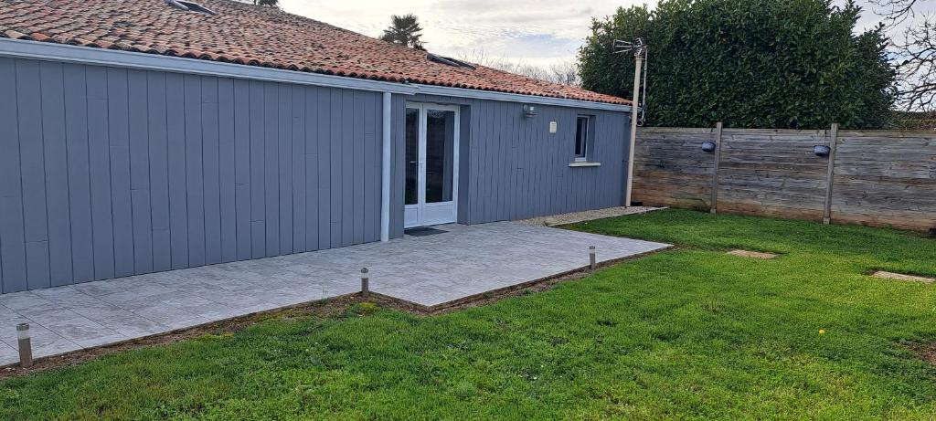a backyard with a gray building and a fence at Gîte du Chemin vert in Taugon