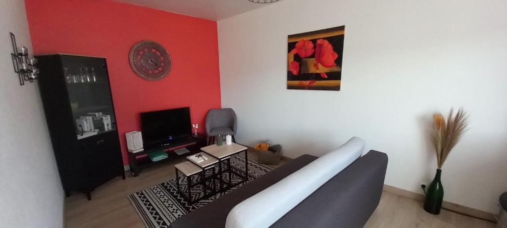 a living room with a couch and a red wall at Le Camus in Belonchamp