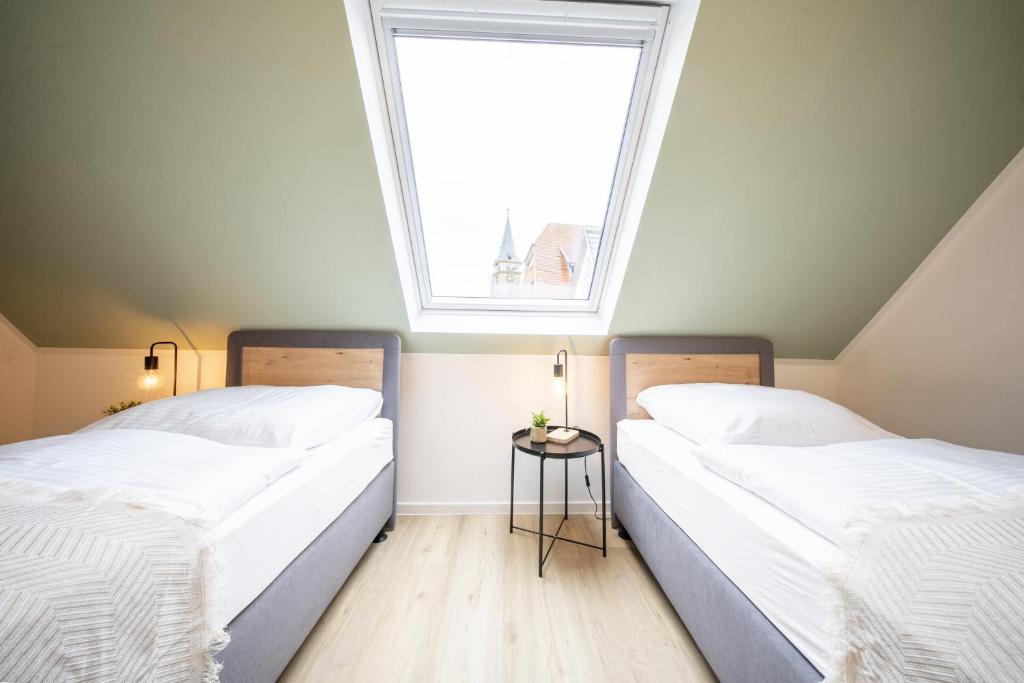 two beds in a room with a window at CharmÖHR Homes in Öhringen