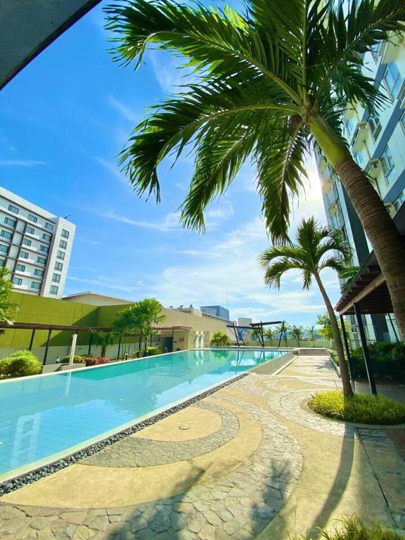 a swimming pool with a palm tree next to a building at Budget Friendly Centrio Tower Studio Unit PoolView in Cagayan de Oro