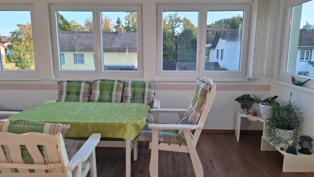 a dining room with a table and chairs and windows at Uschi's guest apartment in Ruderting