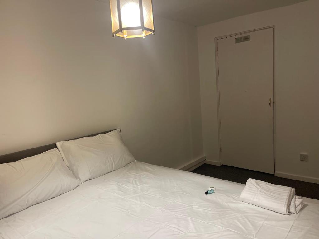 a white bed with two pillows and a bottle on it at Ermihouse in Sheffield