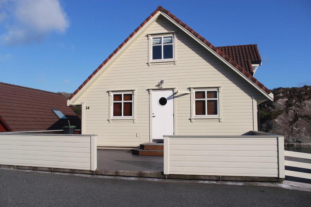 a white house with a fence in front of it at Hus ved sjøen på Bømlo in Bømlo
