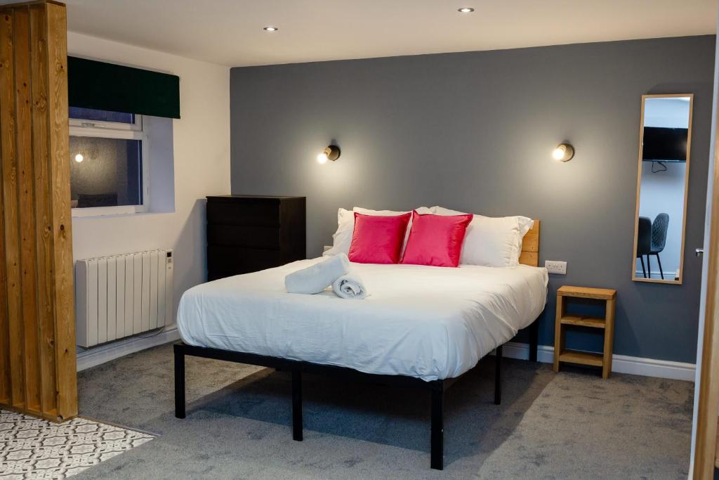 a bedroom with a large bed with pink pillows at Stylish Studio with Parking in Doncaster in Doncaster