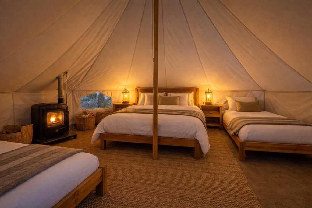 a tent bedroom with two beds and a wood stove at Genesis Mountain Farm in Sandpoint