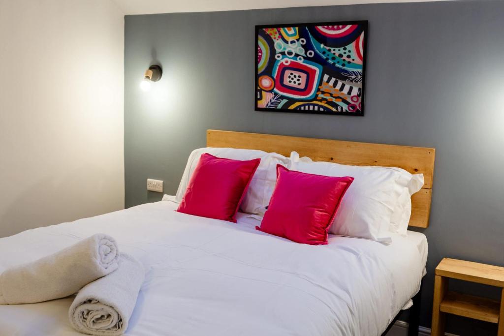 a bedroom with a white bed with pink pillows at Loft-Style Studio with Skylights and Parking in Doncaster