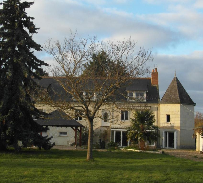 a large white house with a tree in the yard at Les Devants De Rupuanne in Bréhémont