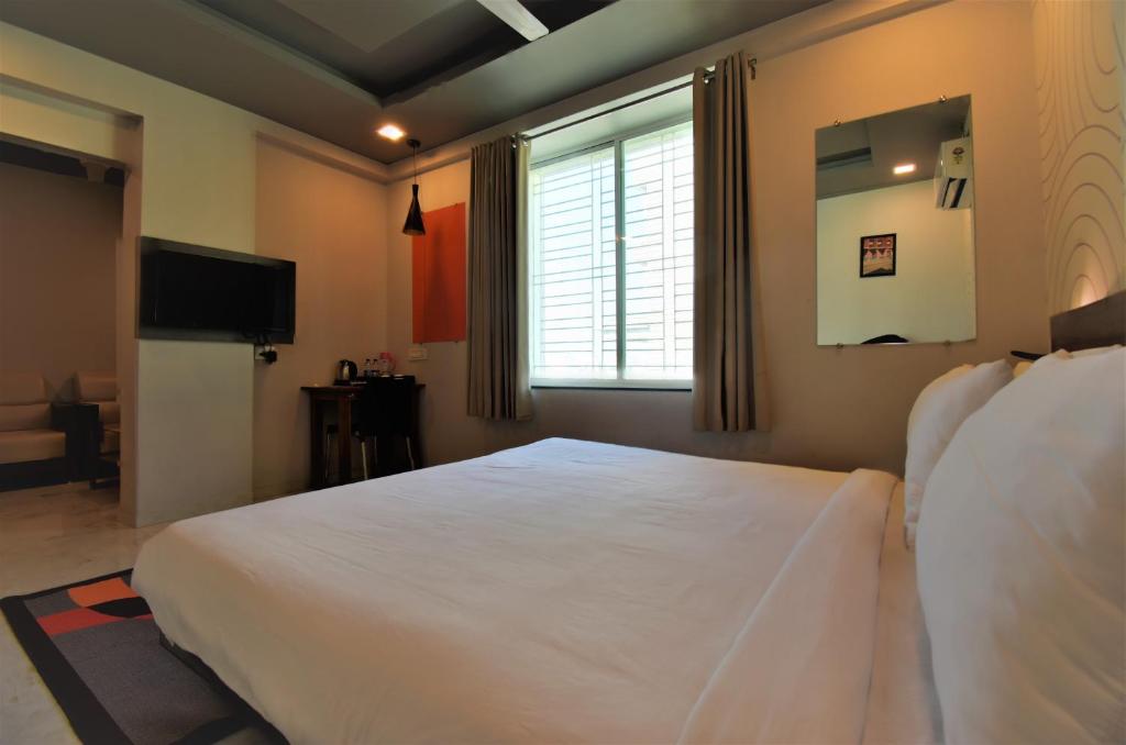 a bedroom with a large white bed and a window at Hotel Manomay in Nagpur