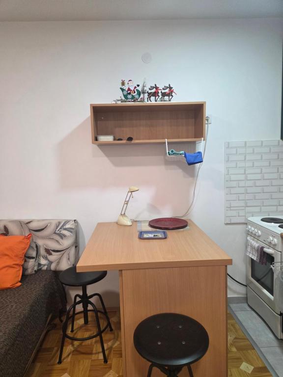 a small kitchen with a table and a bed at Prelep mali stan sa terasom in Petrovaradin