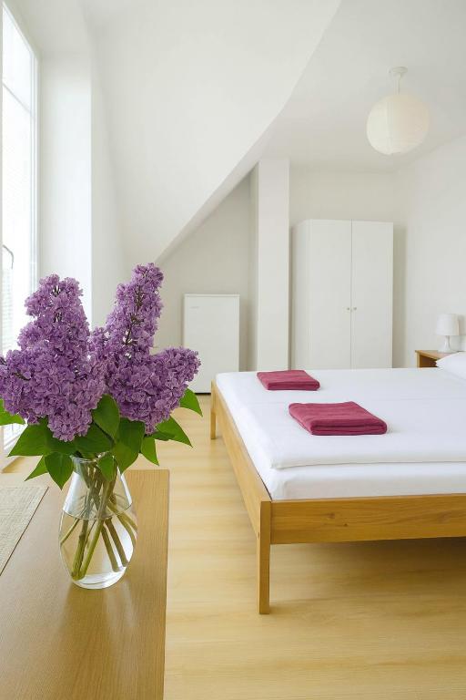 a bedroom with a bed with purple flowers in a vase at Penzion Zacha se sklípkem in Vracov