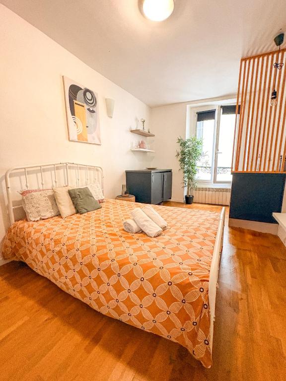 a bedroom with a large bed with a orange comforter at À deux pas du métro in Paris