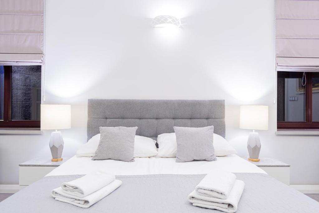 a white bedroom with a large white bed with two pillows at Kamienica Pod Neptunem - Rynek Puck - Śniadanie w cenie - 200m do Molo in Puck