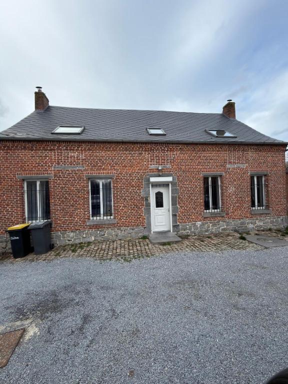 a red brick house with a white door at Maison de village in Mecquignies