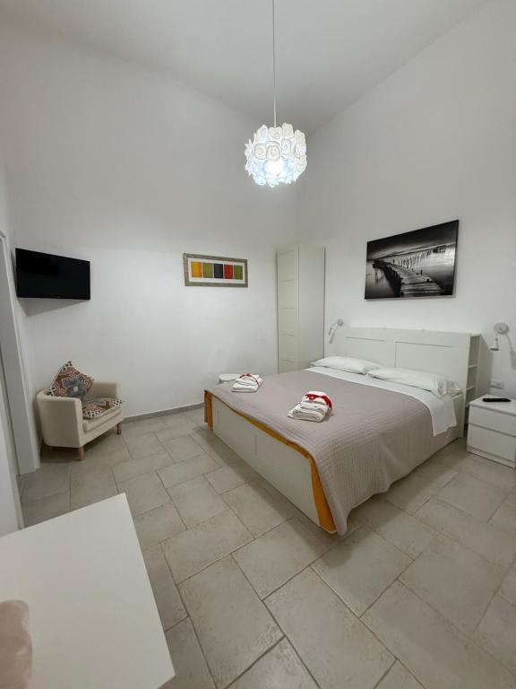 a white bedroom with a large bed and a chandelier at Apulian Dreams in Brindisi
